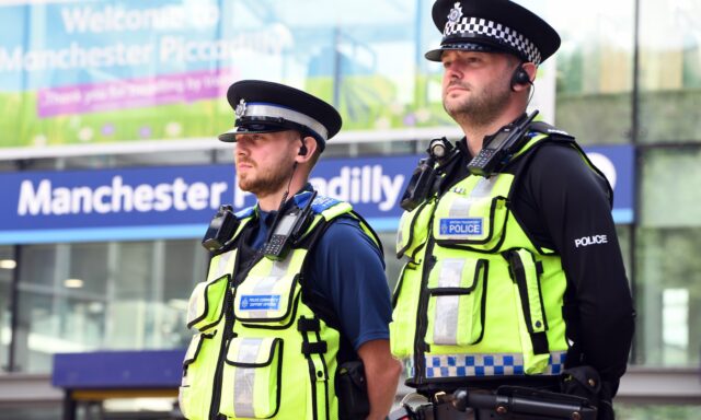 Two British Transport Police officers stand at Manchester Piccadilly