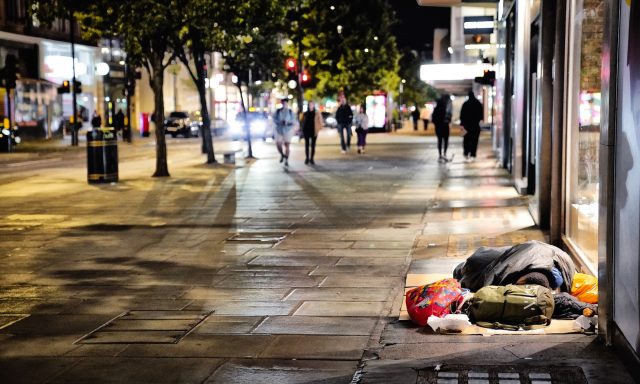 Scene of Oxford Street, London, at night with homeless person sleeping on pavement