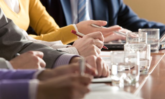 Members of board meeting discuss agenda items