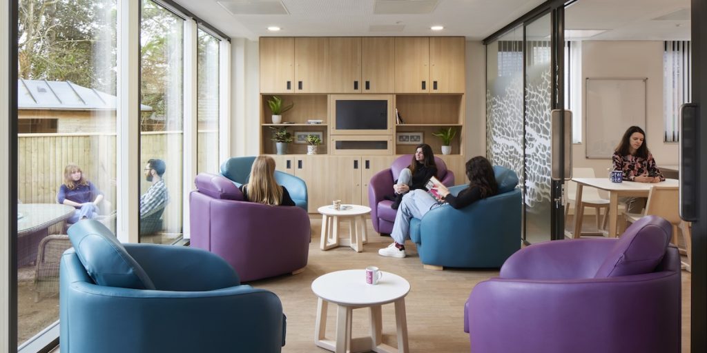 People using a bright communal space in a modern mental health unit designed to encourage social interaction, privacy and wellbeing.