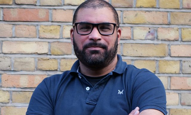 Steve Gilbert OBE, lived experience lead within the Thalamos Responsible Innovation Group, photographed against a brick wall.